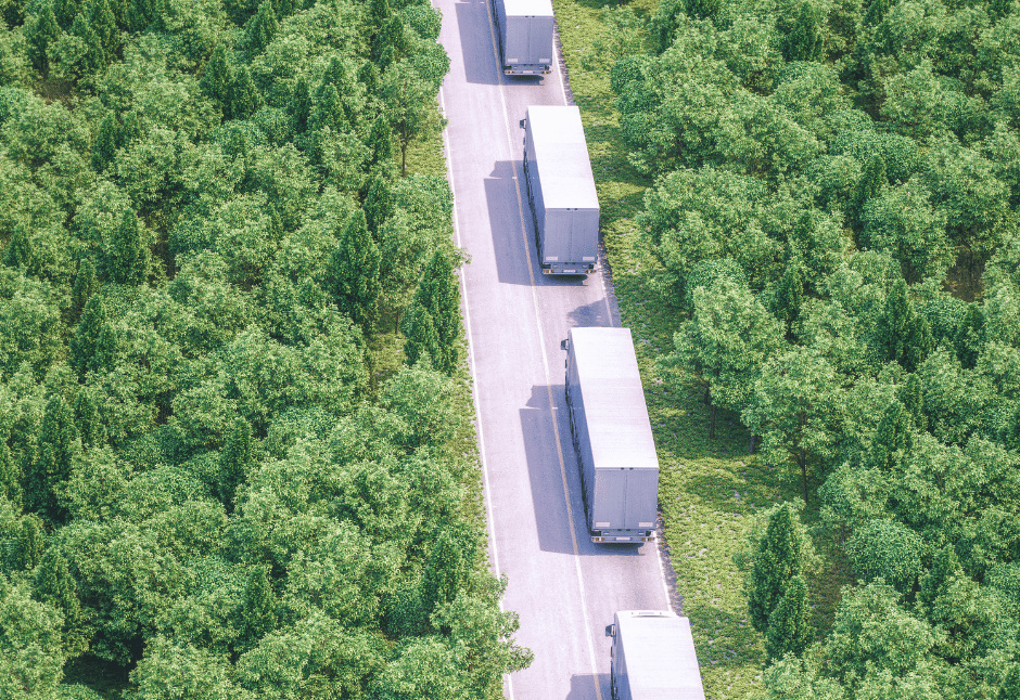 ltl trucking fleet driving down road between budding spring trees